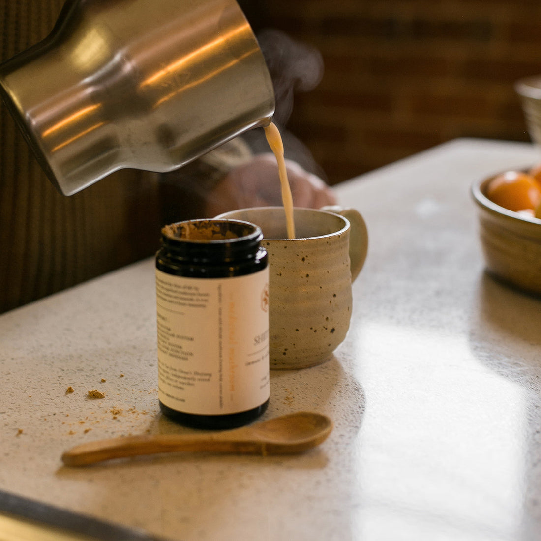 Warm milk poured into a mug beside a jar of SuperFeast herbs